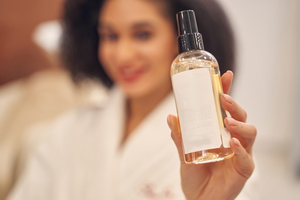 Ragazza che tiene in mano un flacone di cosmetico, simbolo della creazione di una nuova linea cosmetica.