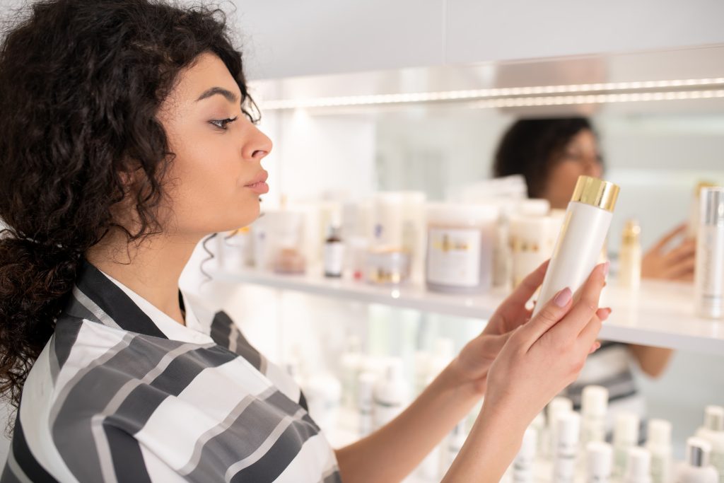 Donna che controlla un flacone di cosmetico, consulenza cosmetica